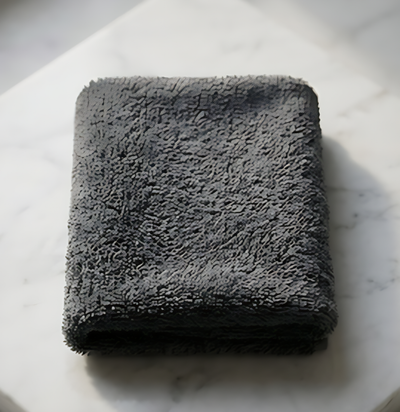 A neatly folded stone grey EXLUX premium skincare facial towel displaying its plush microfiber texture on a white marble surface